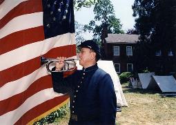 Photo of Jari Villanueva sounding bugle in front of American Flag